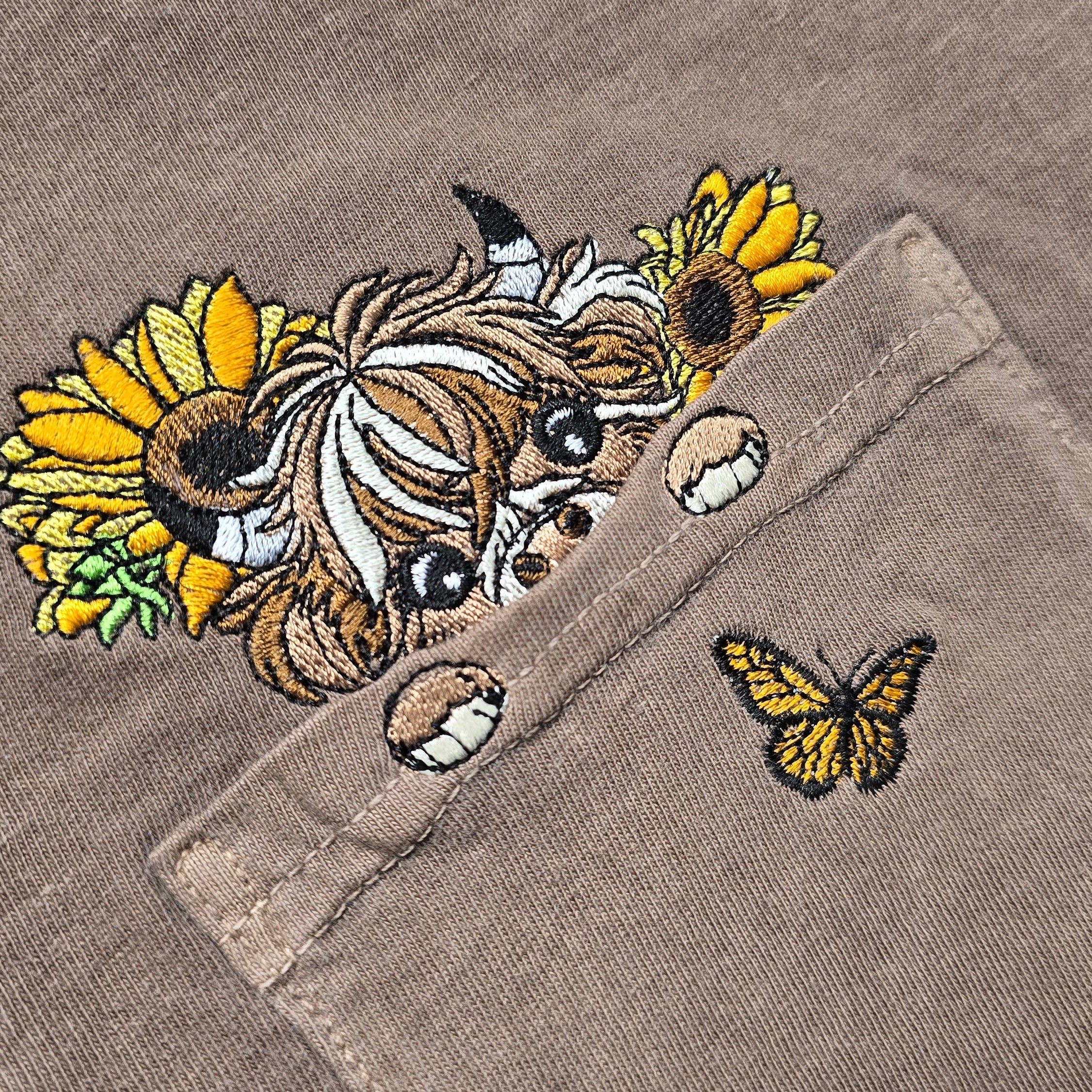 Embroidered design on a fabric with flowers and a butterfly.